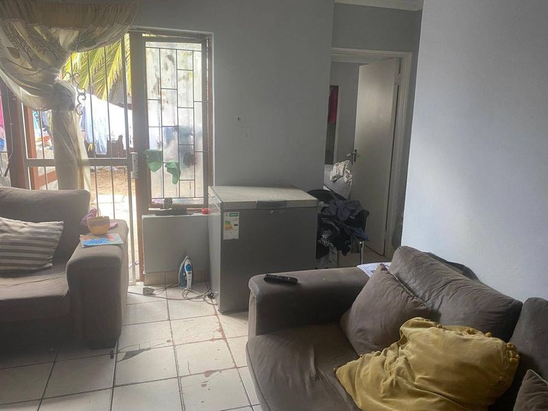 Living room area featuring tiled flooring and a sliding door leading to the exterior, requiring cosmetic updates to improve the overall condition.