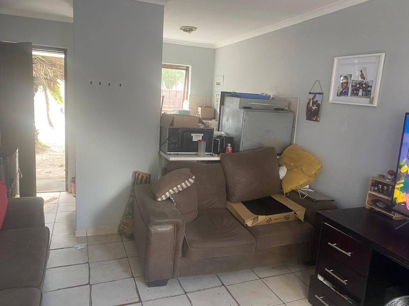 A living area featuring tiled flooring and coved ceilings, providing a functional space with direct access to the exterior.