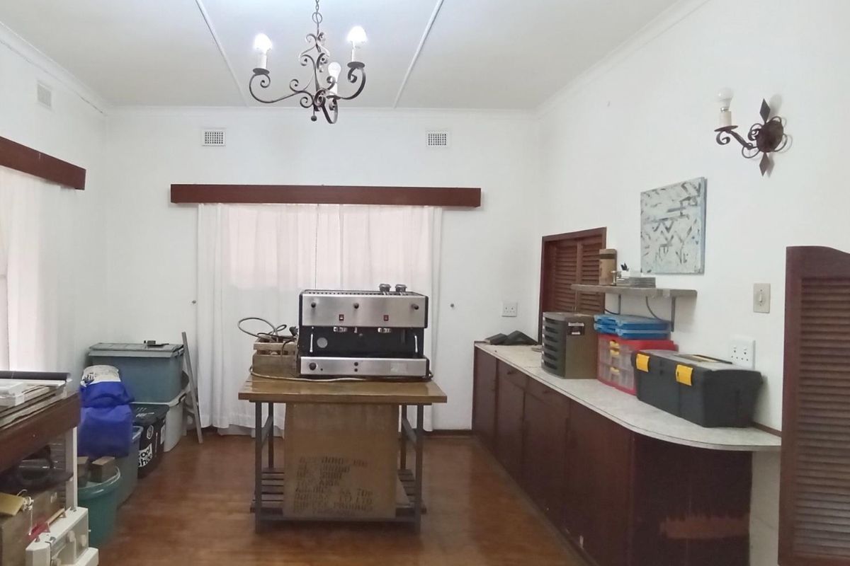 A dated kitchen area featuring built-in cabinetry, laminate countertops, and traditional lighting fixtures, currently used as a utility or workspace.
