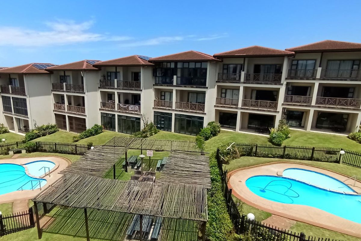 Aerial view of an apartment complex featuring multiple swimming pools, landscaped gardens, pergolas, and private balconies for each unit.