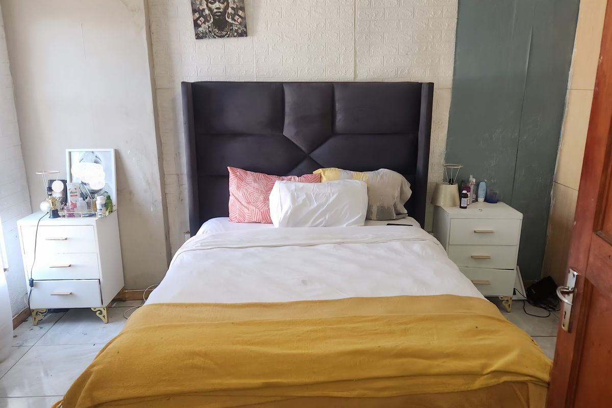 A bedroom featuring tiled flooring, decorative ceiling cornices, and textured wall paneling, requiring cosmetic updates to improve the overall finish and aesthetic appeal.
