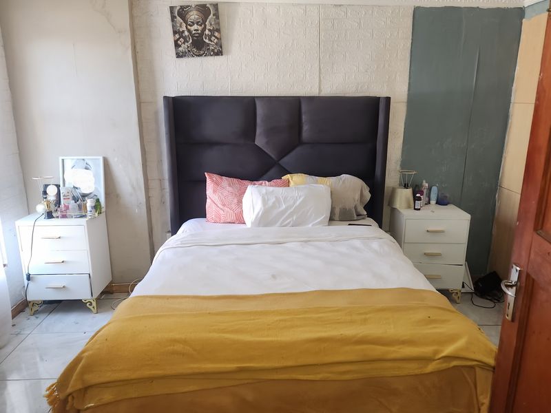 A bedroom featuring tiled flooring, decorative ceiling cornices, and textured wall paneling, requiring cosmetic updates to improve the overall finish and aesthetic appeal.