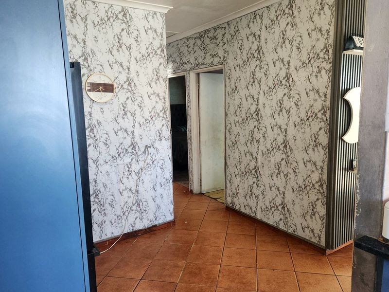 A hallway featuring tiled flooring and decorative wall finishes, providing access to adjacent rooms within the property.