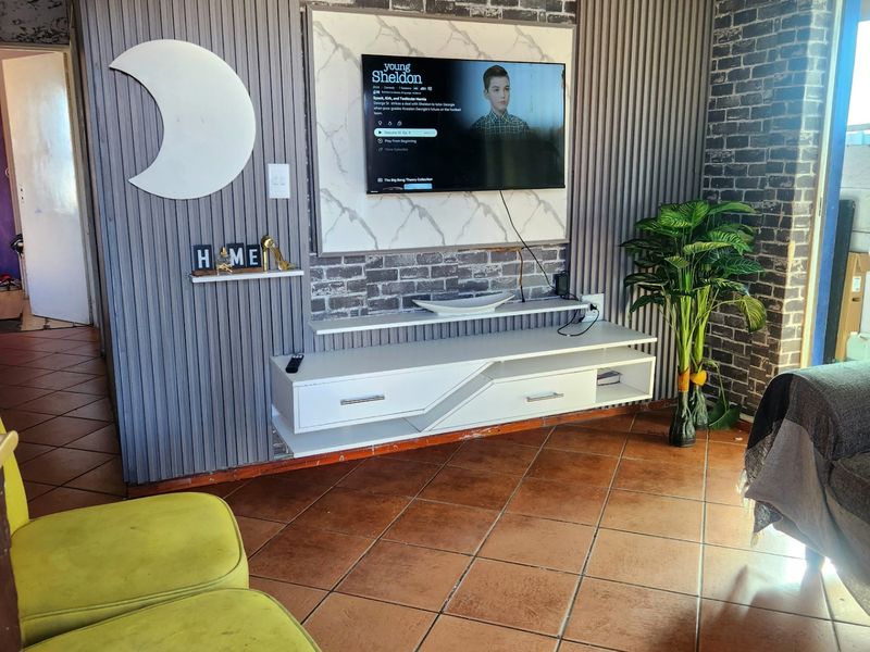 Living room featuring a decorative slatted wall panel, faux brick accents, and a floating media console with tiled flooring.