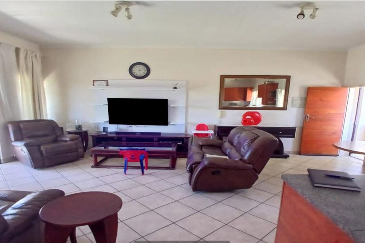 Spacious living room featuring tiled flooring, a built-in media unit, and direct access to an outdoor patio area through sliding glass doors.