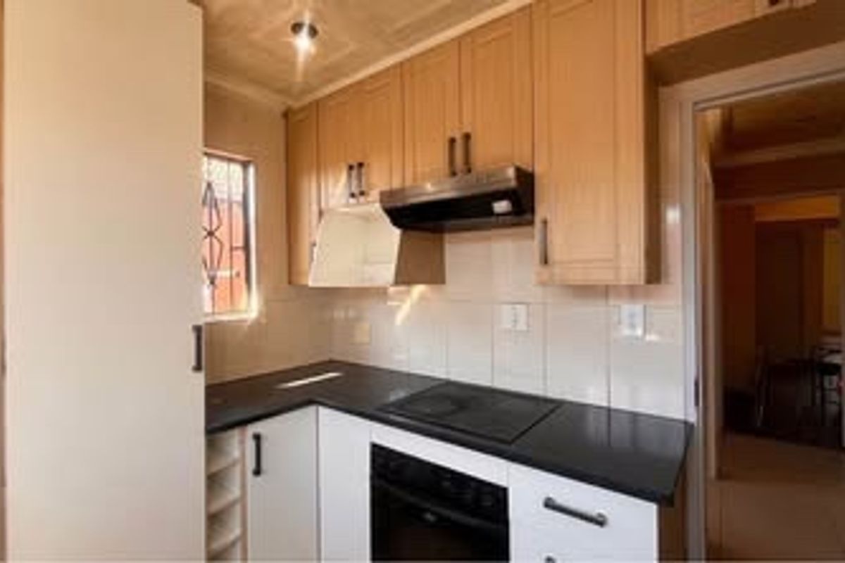 A compact kitchen featuring built-in cabinetry, a dark countertop, an integrated oven, and an extractor fan, offering a functional and clean workspace.