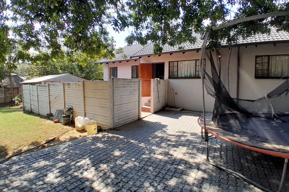 Rear exterior view of the property featuring a paved courtyard, precast boundary wall, and tiled roof structure.