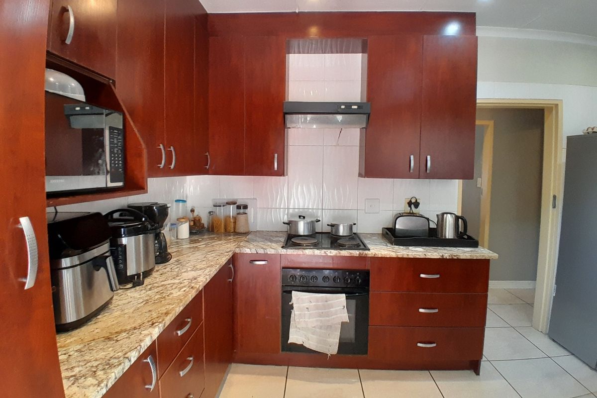 A functional kitchen featuring dark wood cabinetry, granite countertops, a built-in oven with hob, and tiled flooring.