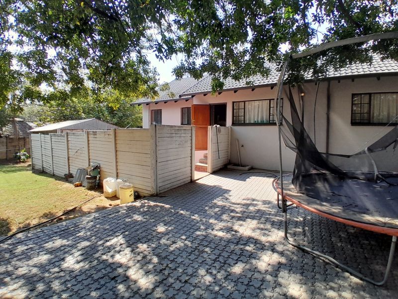 Rear exterior view of the property featuring a paved courtyard, precast boundary wall, and tiled roof structure.