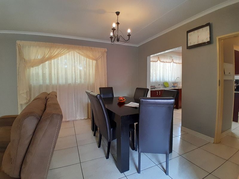 Open plan dining area featuring tiled flooring and a chandelier, with a view into the adjacent kitchen space.