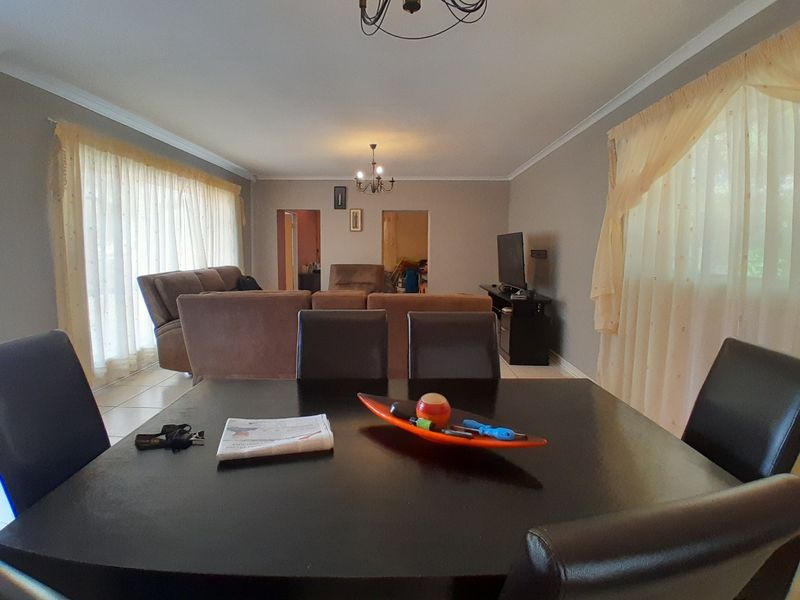 Spacious open-plan living and dining area featuring tiled flooring and neutral wall tones, providing a versatile layout for family living.