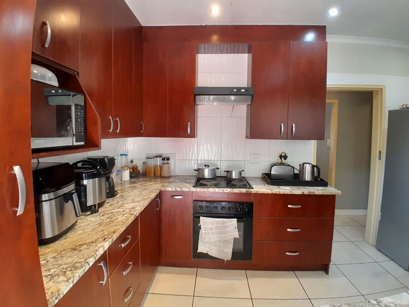 A functional kitchen featuring dark wood cabinetry, granite countertops, a built-in oven with hob, and tiled flooring.