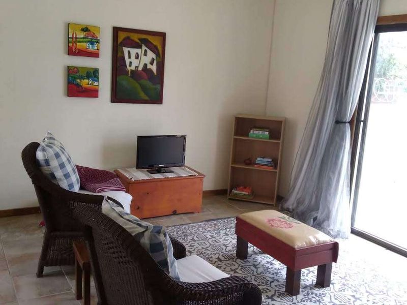 A comfortable living room featuring tiled flooring and a large sliding glass door that provides access to the outdoor area.