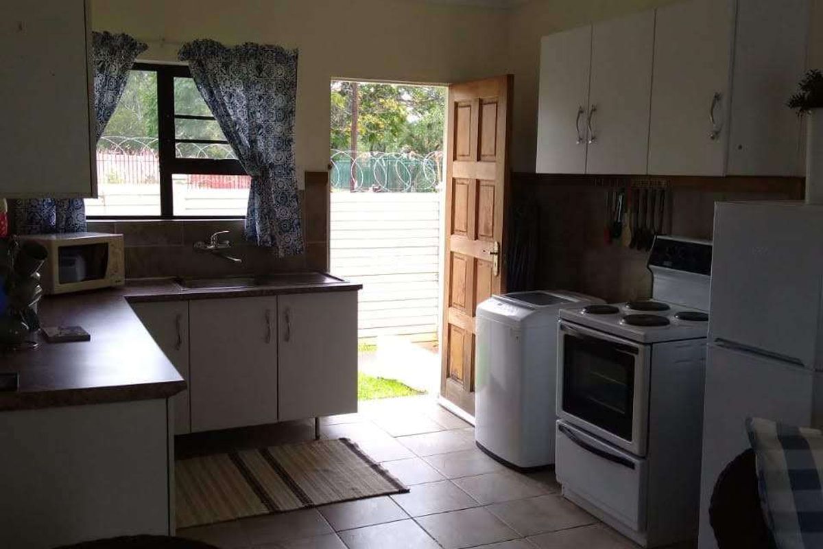 A functional kitchen featuring built-in cabinetry, laminate countertops, and tiled flooring, with direct access to the exterior.