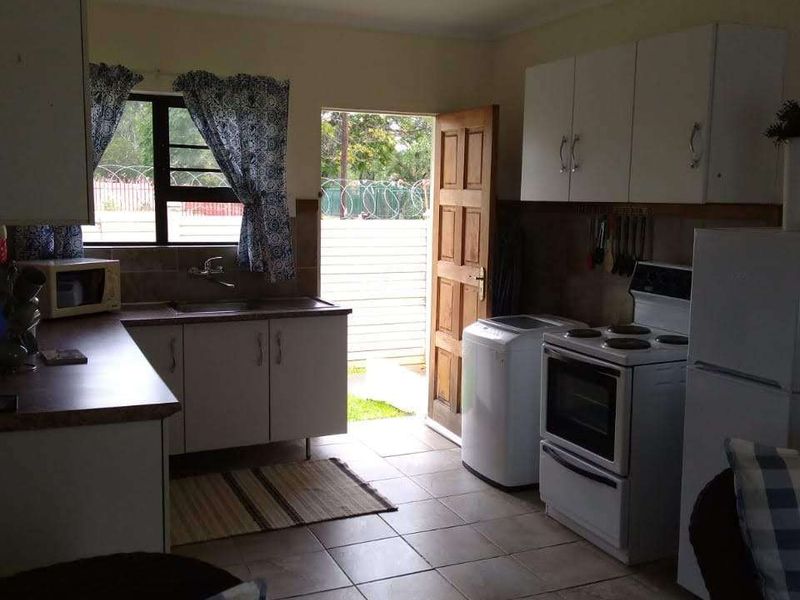 A functional kitchen featuring built-in cabinetry, laminate countertops, and tiled flooring, with direct access to the exterior.