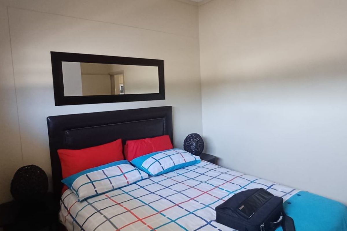 A functional bedroom featuring neutral wall finishes and a window with security bars.
