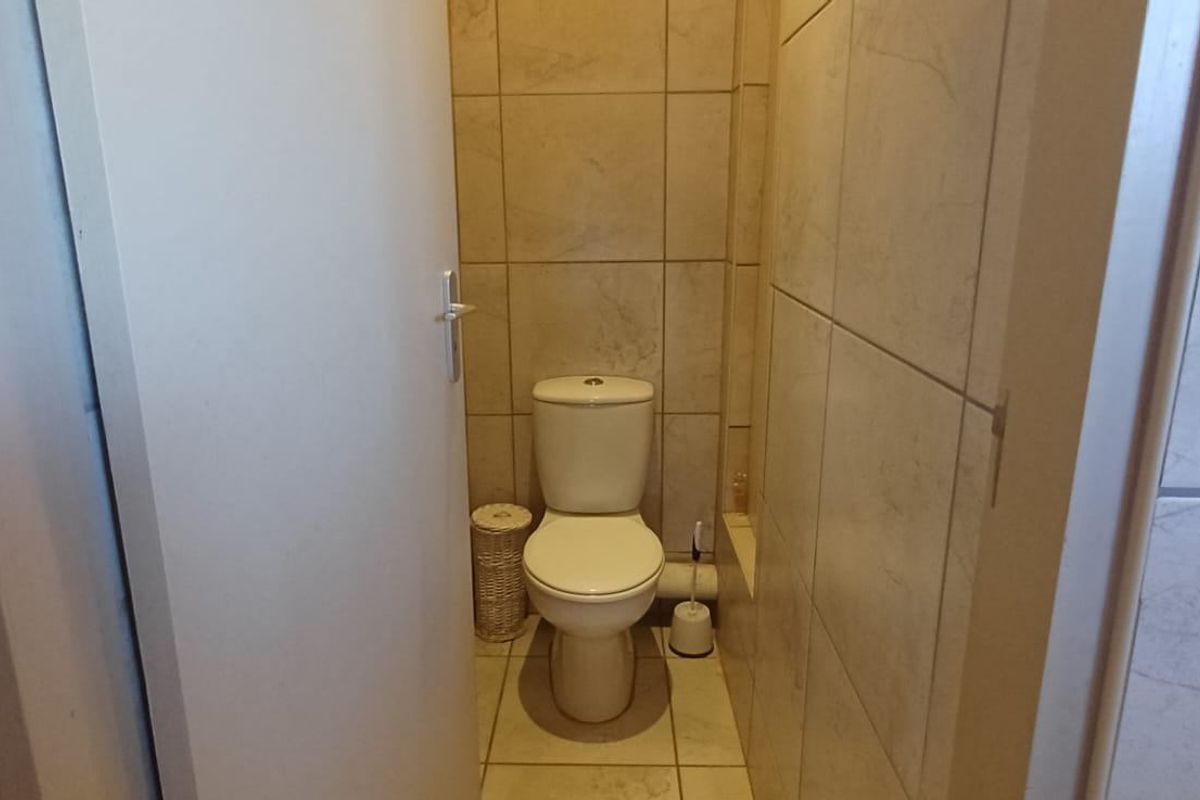 A compact guest toilet featuring floor-to-ceiling wall tiling and a standard ceramic toilet suite.