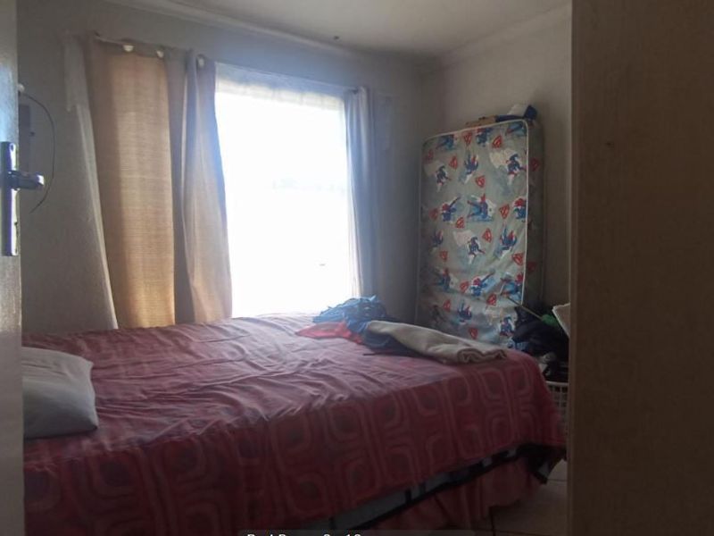 A standard bedroom featuring a window with curtains and a doorway entrance.