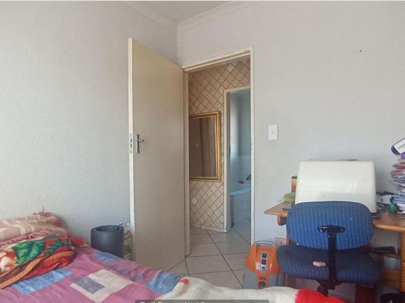 A bedroom featuring tiled flooring and access to an adjacent bathroom, requiring cosmetic updates to improve the overall aesthetic and condition.