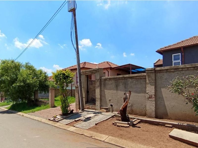 Street view of the property showing the perimeter wall, pedestrian gate, and paved verge area.