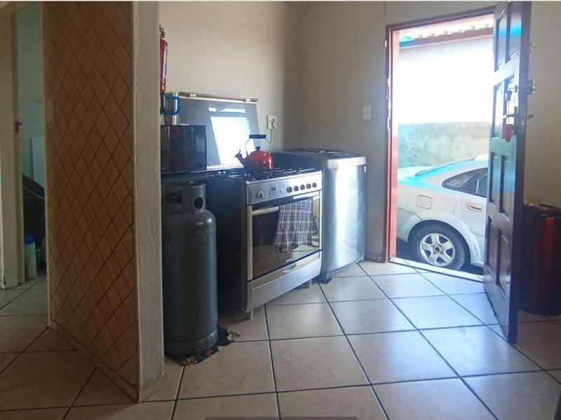 A functional kitchen area featuring tiled flooring and a gas stove, with direct access to the exterior.