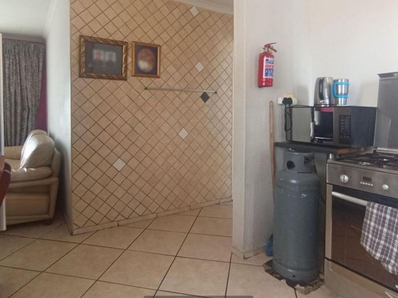 A functional kitchen area featuring tiled flooring, a gas stove, and a decorative tiled feature wall.