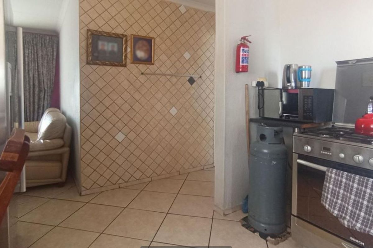 A functional kitchen area featuring tiled flooring, a gas stove, and a decorative tiled feature wall.