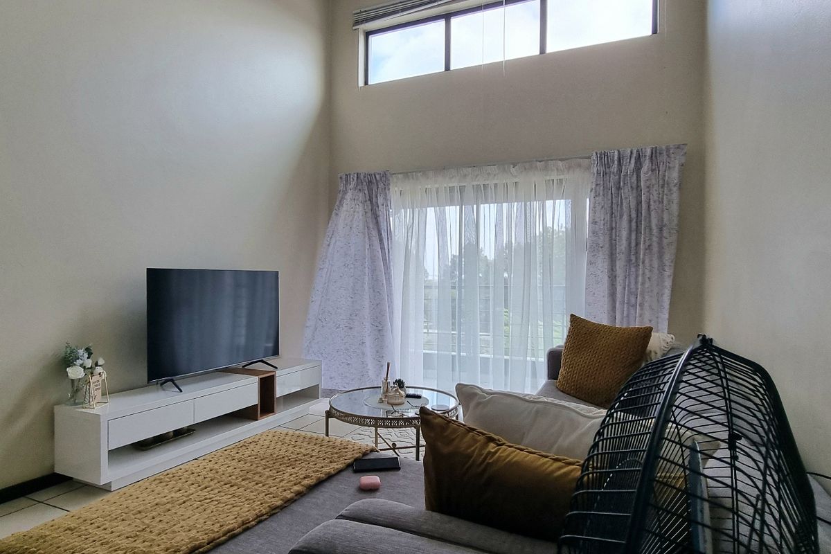 Spacious living room featuring high ceilings, large windows for natural light, and tiled flooring, creating an airy and open atmosphere.