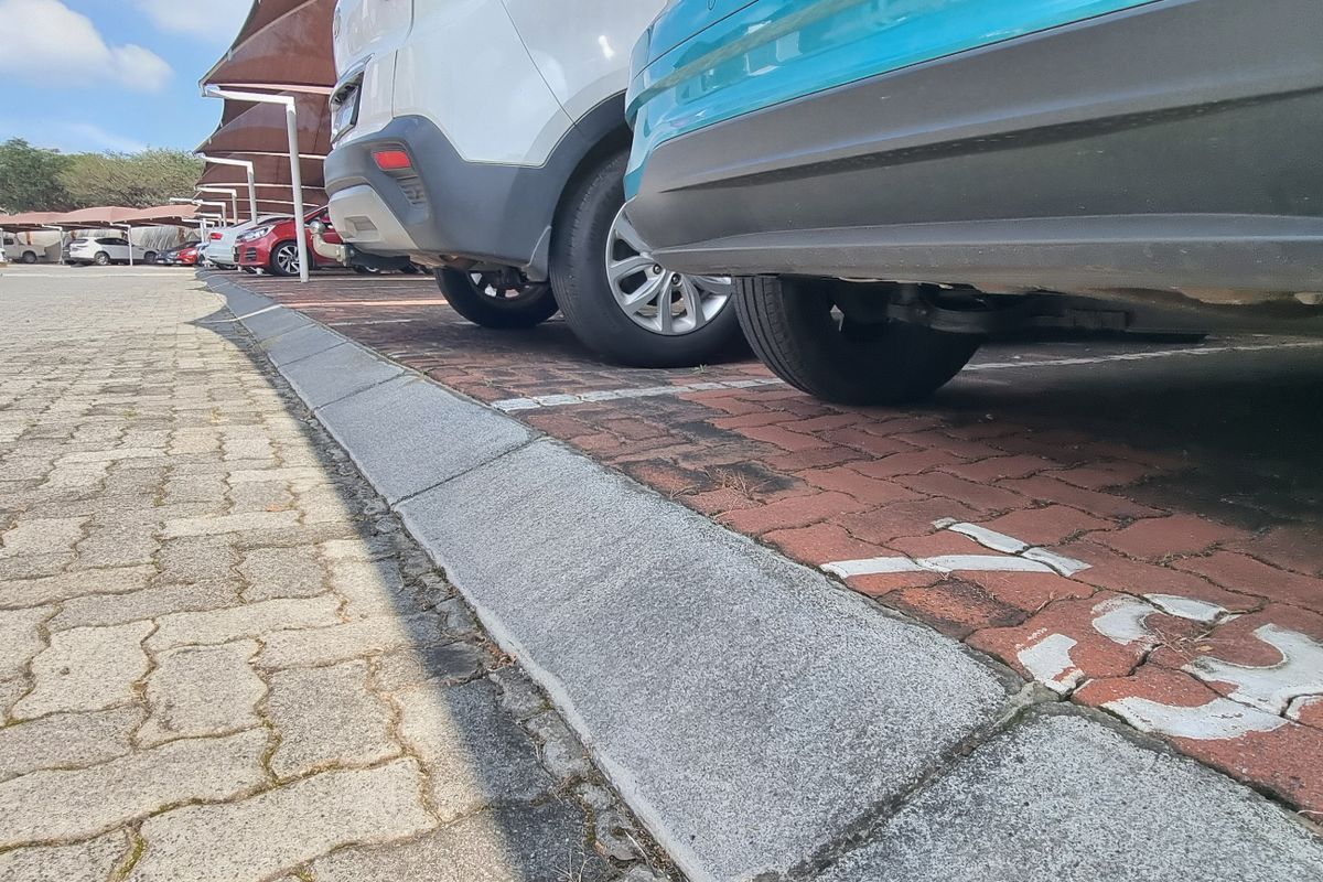 An outdoor parking area featuring paved surfaces and designated parking bays with shade structures.