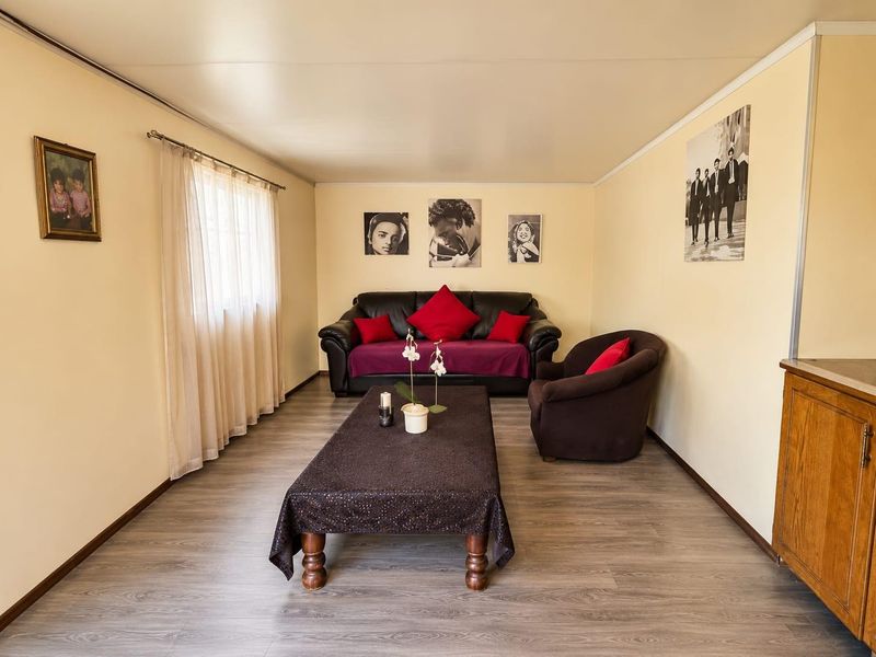 A well-lit living room featuring modern laminate flooring, neutral wall tones, and a clean, functional layout suitable for comfortable family living.