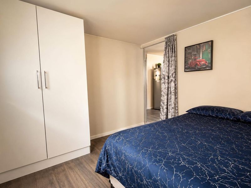 A well-maintained bedroom featuring neutral walls, modern laminate flooring, and a clean, white built-in wardrobe.