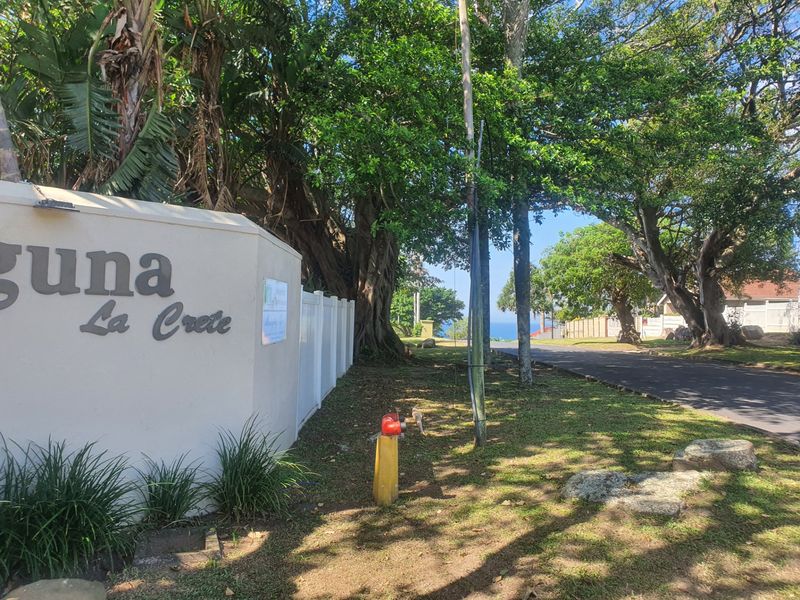 Street view showing the entrance signage for Laguna La Crete complex with mature trees and paved road access.