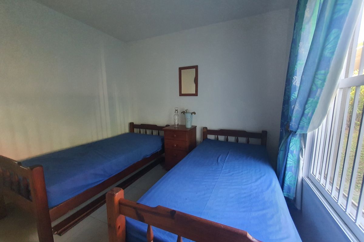 A functional bedroom featuring tiled flooring and a large sliding window that allows for natural light.