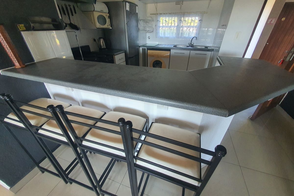 Functional kitchen featuring a breakfast bar, laminate countertops, built-in cabinetry, and tiled flooring, offering a practical layout for daily use.