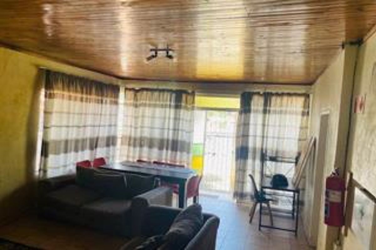 Living area featuring a timber-clad ceiling and tiled flooring, providing a functional space with direct access to the exterior.