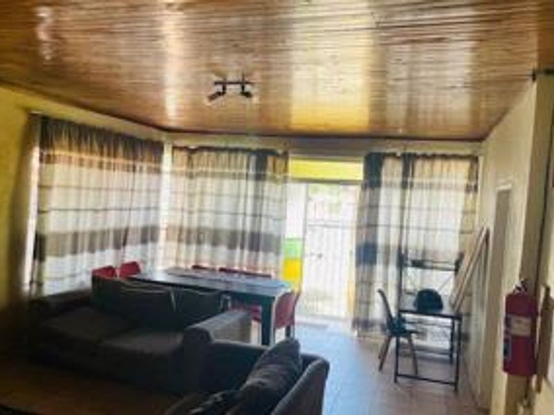 Living area featuring a timber-clad ceiling and tiled flooring, providing a functional space with direct access to the exterior.