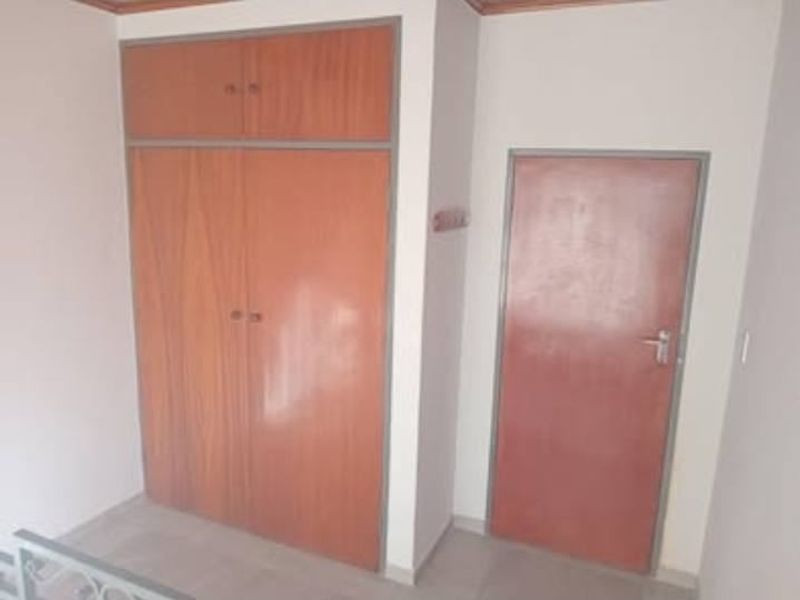 A bedroom interior featuring built-in wooden cupboards and a standard internal door, presenting a clean and functional space ready for personalization.