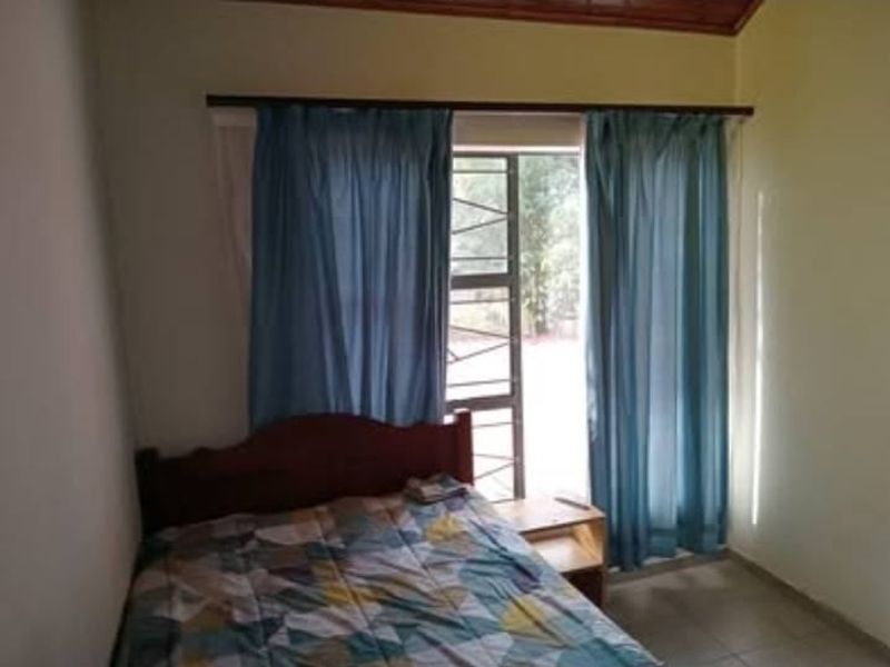 A bedroom featuring tiled flooring, a timber ceiling trim, and a window with a security gate.