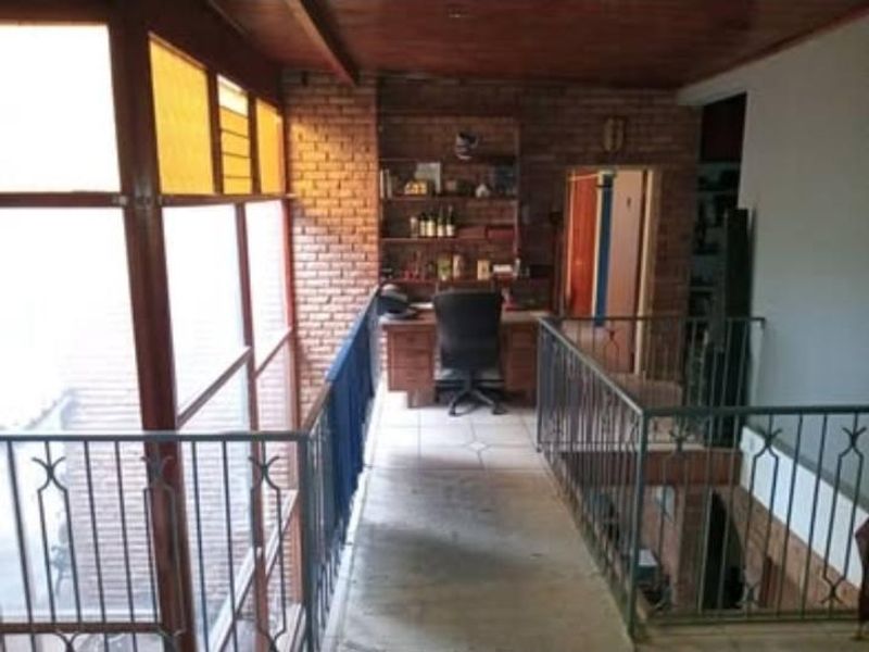 An elevated office space featuring exposed brick walls, timber ceiling, and metal balustrades overlooking the lower level.
