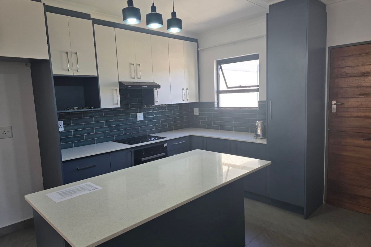 Modern kitchen featuring two-tone cabinetry, quartz countertops, a central island, and integrated appliances with a stylish tiled backsplash.