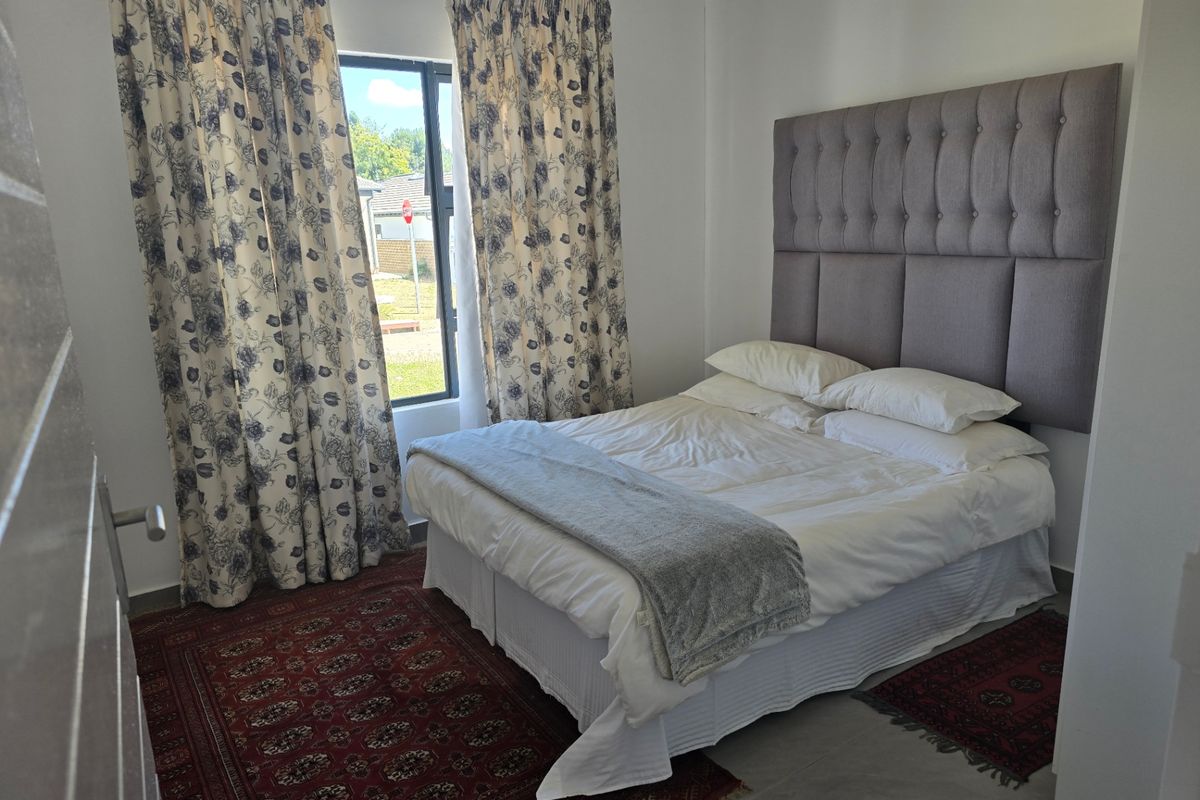A well-lit bedroom featuring tiled flooring and a large window with views of the exterior.