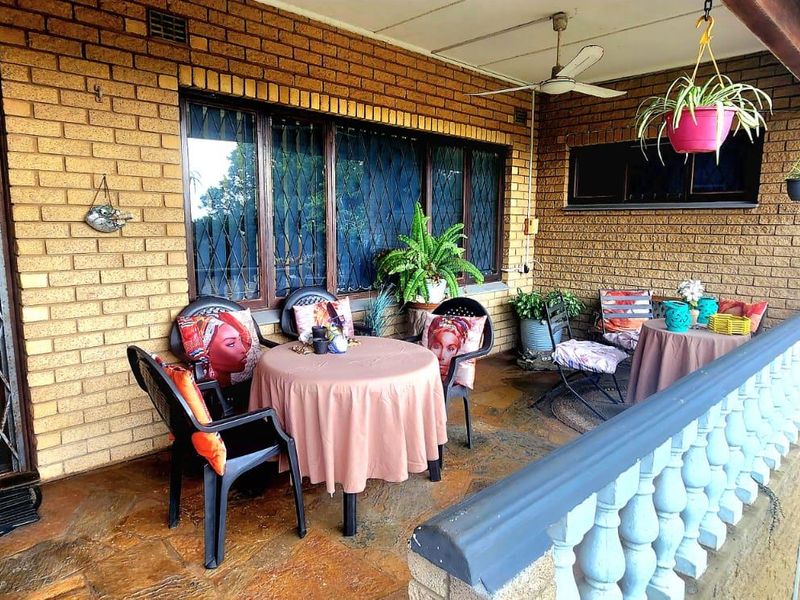 A covered patio area featuring brick walls, security gates, and a balustrade, providing a functional outdoor space for relaxation.