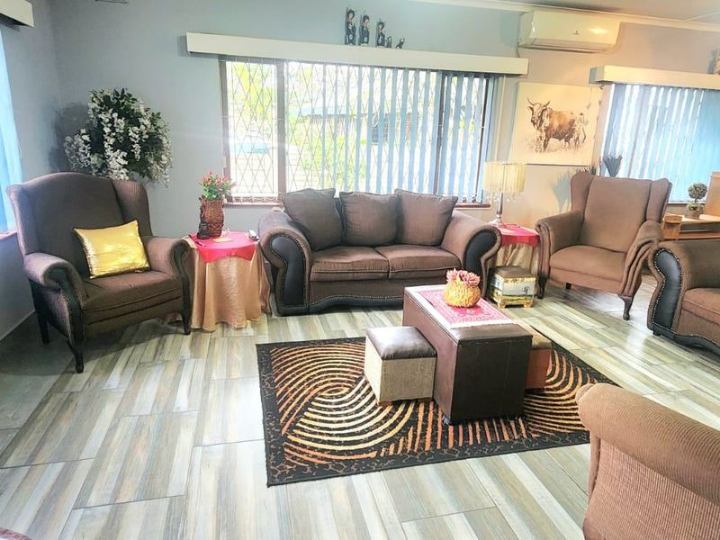 Spacious living room featuring tiled flooring, vertical blinds, and a wall-mounted air conditioning unit.