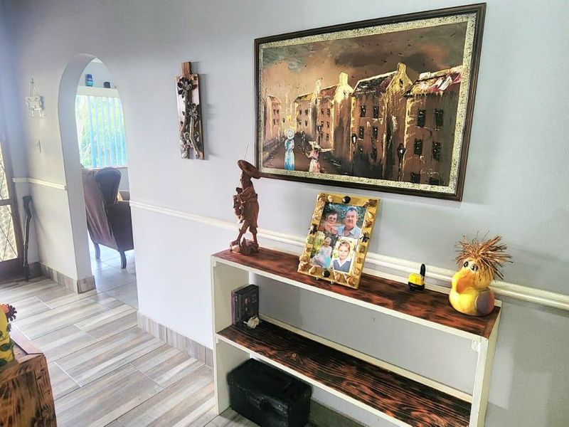 A bright hallway featuring tiled flooring, a decorative chair rail, and an arched entryway leading to an adjacent living space.