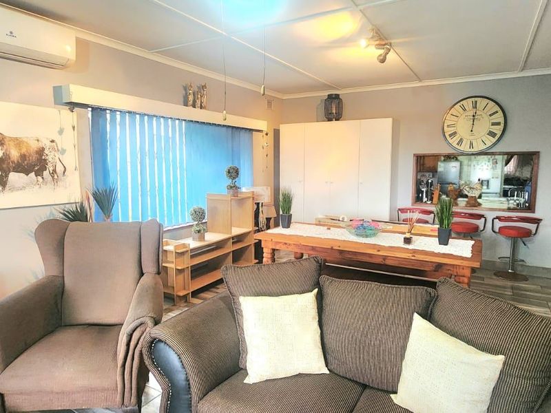 Open-plan living and dining area featuring tiled flooring, split-system air conditioning, and a convenient pass-through window connecting to the kitchen space.