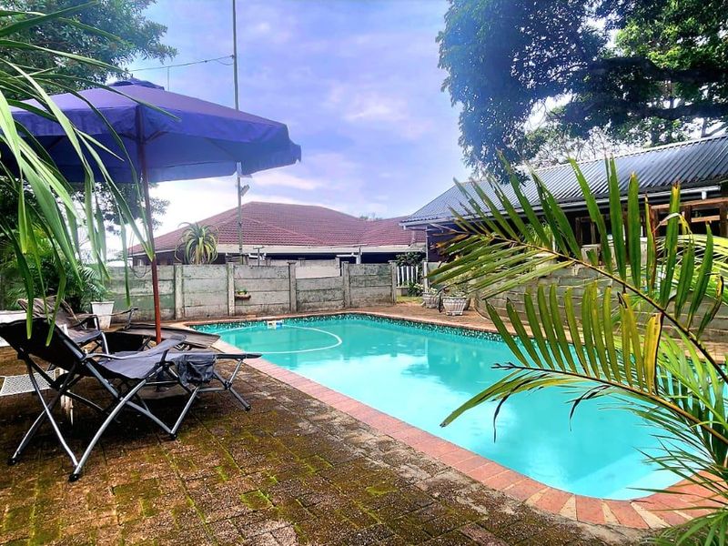 Outdoor pool area featuring a swimming pool with paved surround, enclosed by precast concrete and timber boundary walls.