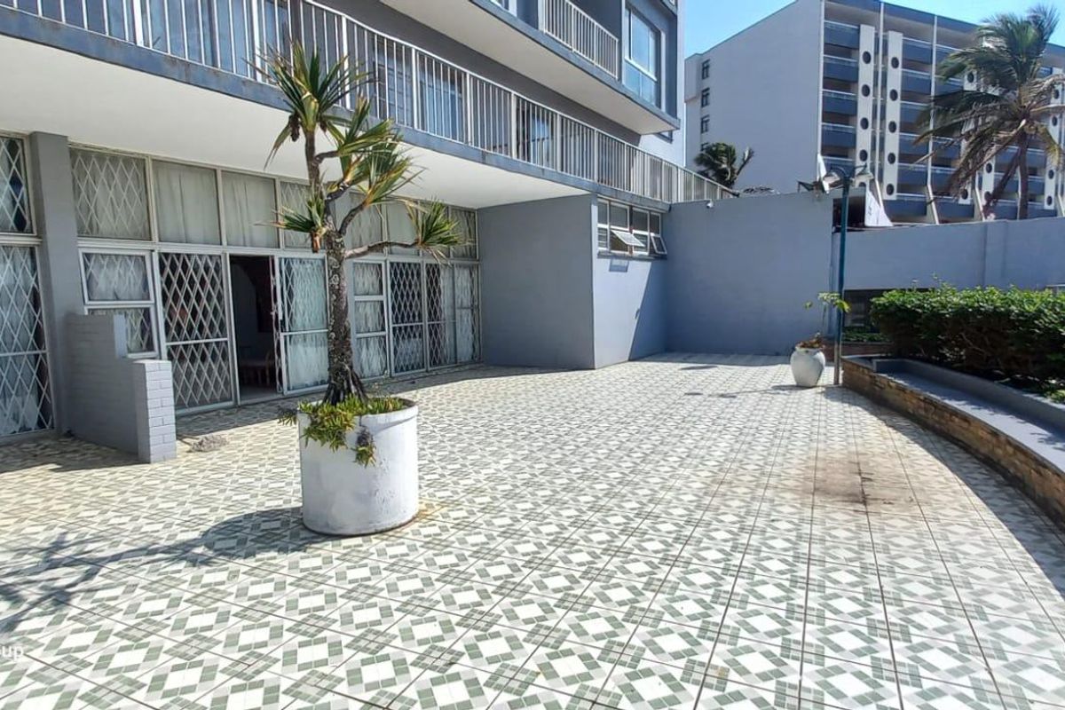 Spacious outdoor patio area featuring tiled flooring, security gates, and a low retaining wall, offering potential for an inviting entertainment space.