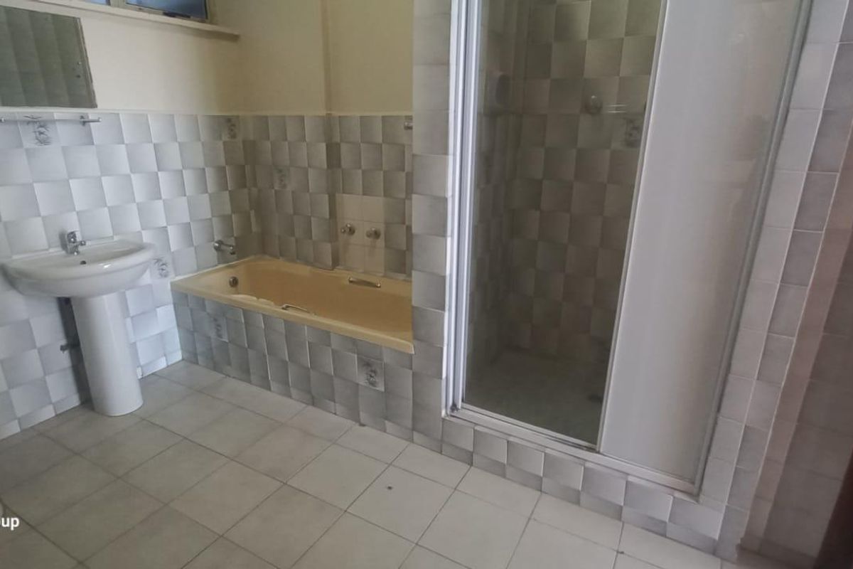 A dated bathroom featuring a pedestal basin, built-in bathtub, and separate shower enclosure with tiled walls and flooring.