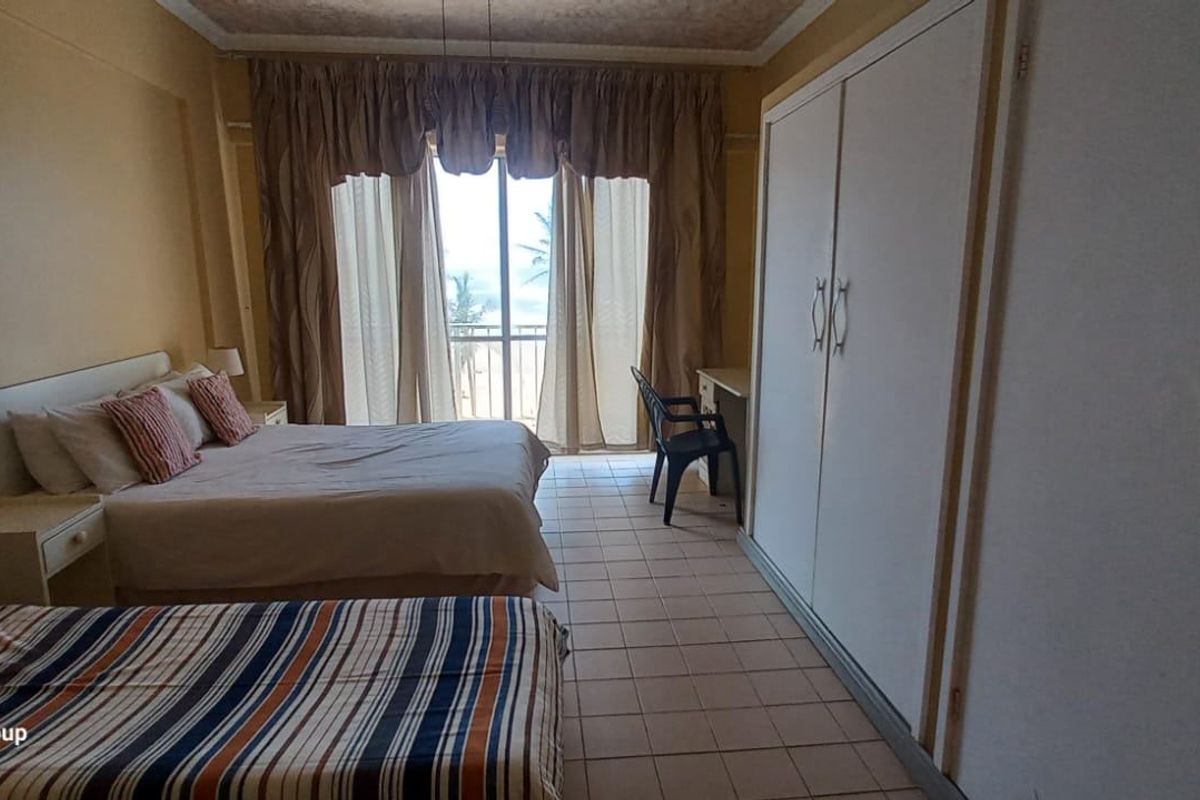 Spacious bedroom featuring built-in cupboards, tiled flooring, and a sliding glass door providing access to a balcony with natural light.