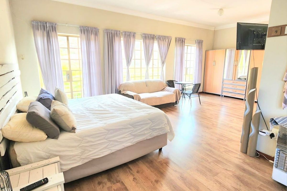 Spacious bedroom featuring laminate flooring, built-in wardrobe storage, and multiple sets of french doors providing natural light.